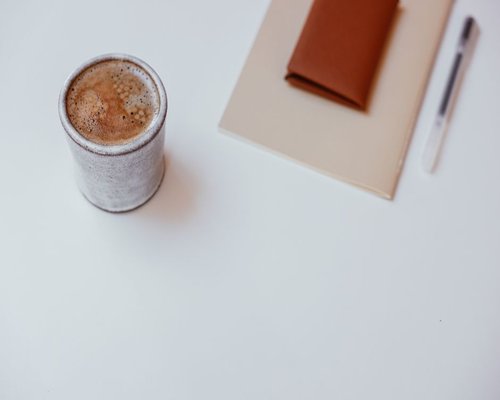 A cup of coffee and a notebook on an office desk