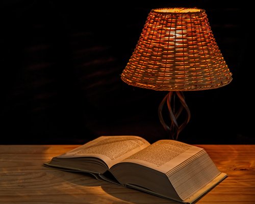 A desk lamp illuminating an open book clearly